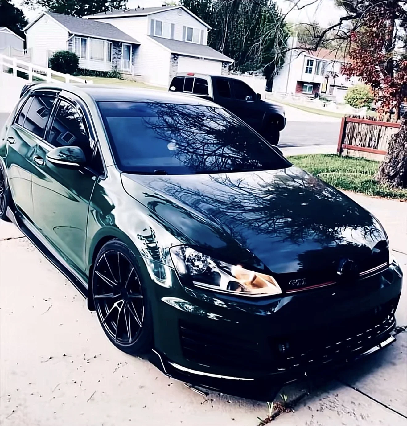 Same Volkswagen GTI wrapped in a deep green-black color-shift vinyl finish